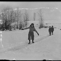 Isbana, skurron: På isen brukade man springa upp en ca 0,5 meter bred och 10-15 meter lång bana som skulle hållas öppen, ren och hal. Pojkarna brukade använda denna isbana till att "skurr". Därför kallades banan "skurron". Man sprang några steg, tog fart och kanade längs med banan. Skurrbanorna var mycket vanliga på ån vintertid, men kunde även göras på isig mark. Närpes år 1938. Upphovsman: Maximilian Stejskal. Svenska Litteratursällskapets samlingar, sls.finna.fi SLS 487 b b, 04